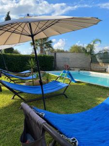 duas cadeiras e um guarda-sol ao lado de uma piscina em Case Vacanze Gnocchi em Trappeto