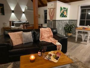 a living room with a black leather couch and a table at Trawool Shed Cottages, Cafe and Restaurant in Seymour