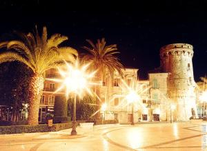 a street with palm trees and a castle at night at Le Maioliche in Vasto +13 photos