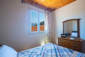 ein Schlafzimmer mit einem Bett, einem Fenster und einer Kommode in der Unterkunft Konstantino's House in Áyios Ilías