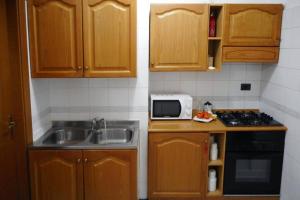 eine Küche mit Holzschränken, einer Spüle und einer Mikrowelle in der Unterkunft Casa Bahia in Marina di Davoli