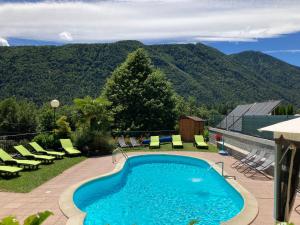a swimming pool with chairs and mountains in the background at RESIDENZA VALLE VIGEZZO in Santa Maria Maggiore
