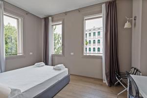 a bedroom with a bed and two windows at MyPlace Treviso Vittoria in Treviso
