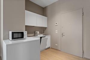 a kitchen with white cabinets and a microwave on a counter at JOIVY Treviso Vittoria in Treviso