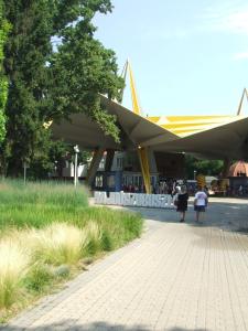 a building with awning and people walking down a sidewalk at Welcome Apartman in Hajdúszoboszló