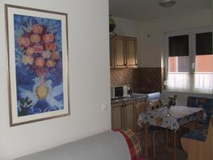 ハイドゥソボスローにあるWelcome Apartmanのテーブル付きのキッチン、壁に絵画