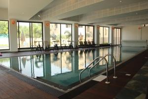 a swimming pool with tables and chairs in a building at Tathastu Pench in Khawāsa