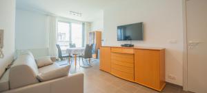 a living room with a tv and a couch and a table at Studio met groot zonneterras centrum Oostende in Ostend