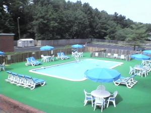 a swimming pool with chairs and tables and umbrellas at Express Airport Inn in Sandston