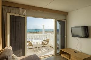 a living room with a television and a balcony with a table at Galera Beach Apartamentos in Corralejo