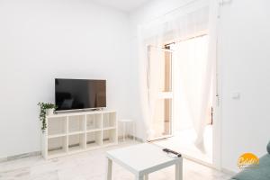 a white living room with a tv and a table at Casa Patio La Viña by Cadiz Time in Cádiz