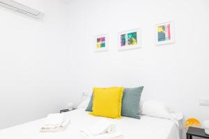 a white bedroom with a yellow pillow on a bed at Casa Patio La Viña by Cadiz Time in Cádiz