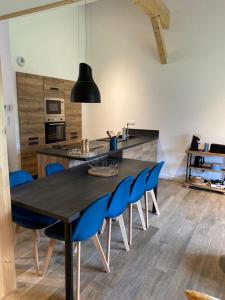 a kitchen with a black table and blue chairs at Résidence les biches in Xonrupt-Longemer