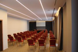 a conference room with red chairs and a screen at Fiore Hotel in Kavajë