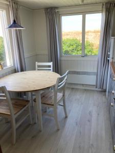 a dining room with a table and chairs and two windows at Slimmingegården in Skurup