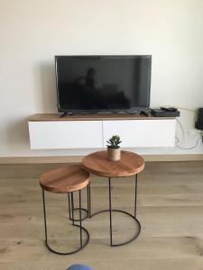 una mesa y dos taburetes frente a una TV en Work or holiday nieuw studio Santhooft, en Nieuwpoort