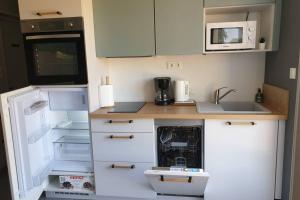 a small kitchen with a refrigerator and a microwave at Agréable logement pour 4 pers à deux pas de Verdun in Haudainville