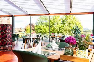 un restaurante con mesas, sillas y ventanas en HIRSCHEN OBERKIRCH - Design Boutique Hotel, en Oberkirch