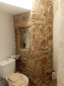 a bathroom with a stone wall and a toilet at TerraFazBem in Marvão