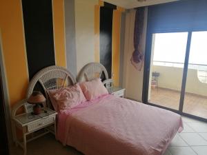 um quarto com uma cama com lençóis cor-de-rosa e uma janela em Akwass Marina Assilah em Asilah