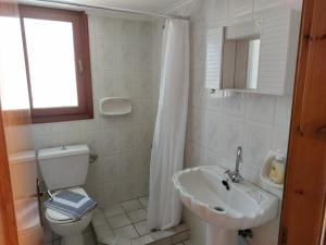 a white bathroom with a toilet and a sink at Joanna Rooms in Skala Eresou