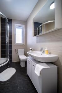 a bathroom with a sink and a toilet and a tub at Apartman Dora in Rab