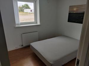 a white bedroom with a bed and a window at Ferielejlighed ved Vilsted Sø in Løgstør