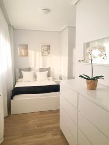 um quarto com uma cama num quarto branco em Apto Vistas Mar y Monte Céntrico Garaje Incluido em Castro-Urdiales