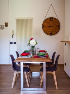 mesa de comedor con sillas y reloj en la pared en Appartamento nel cuore dell'Appennino Tosco-Emiliano, en San Benedetto Val di Sambro