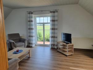 a living room with a couch and a tv at Landsitz Riekenshof in Horumersiel in Wangerland