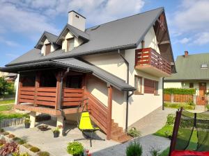 a house with a black roof and a yellow chair at Domek u Jaśka in Głębokie