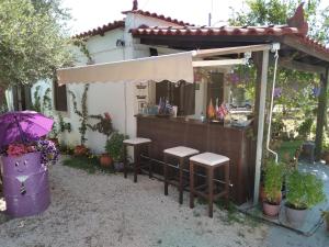 an outdoor bar with stools and an umbrella at LUXURY TRADITIONAL ROOM The Small Bookstore in Kyllini
