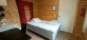 a small bedroom with a bed in a wooden room at Hillside Rooms in Ivalo