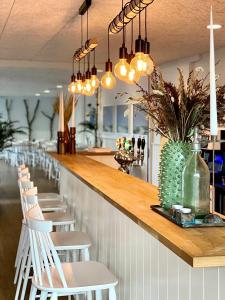 a bar with white chairs and lights at Hotel Marie in Skagen