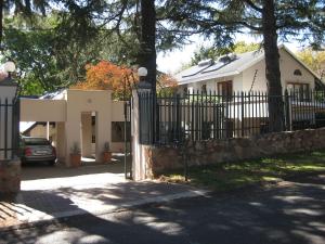 a fence in front of a white house at Craighall Executive Suites in Johannesburg