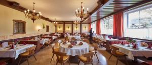 a restaurant with tables and chairs and chandeliers at Landgasthof Klausner in Molln