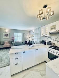 a large kitchen with white cabinets and a chandelier at Cotswold Chic Retreats "Cloud Nine" 5 Star Chipping Campden-Parking-Garden in Chipping Campden