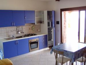 ヴィッラプッツにあるLe Residenze di Porto Coralloのキッチン(青いキャビネット、テーブル、椅子付)