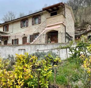 una vieja casa de ladrillo con una escalera delante de ella en B&B Il Poggetto, en Serra SantʼAbbondio