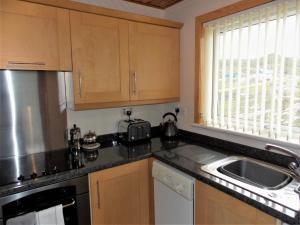 a kitchen with wooden cabinets and a sink and a window at Riverside in Tarbert