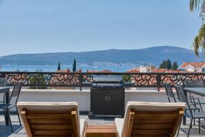 a grill on a patio with chairs and a balcony at Moderna Luxury Apartments with HEATED pool in Tivat