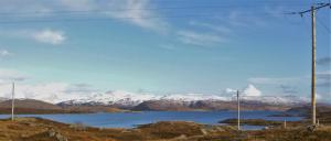 a body of water with snow covered mountains in the background at Riverside in Tarbert