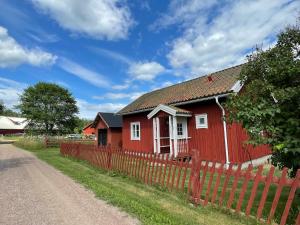 a red house with a fence next to a road at Ekhaga, Hultåkra in Mariannelund