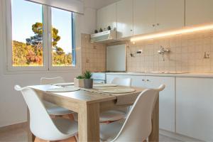a kitchen with a wooden table and white chairs at Summer Feel suites in Poros