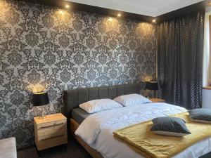 a bedroom with two beds and a wall with wallpaper at Apartamenty Pod Jesionem in Zator