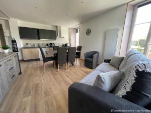 a living room and kitchen with a couch and a table at L'École Buissonnière in Saint-Vigor-le-Grand