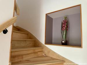 a mirror on a wall with a vase of flowers at L'École Buissonnière in Saint-Vigor-le-Grand