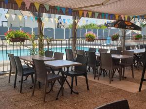 - une rangée de tables et de chaises à côté de la piscine dans l'établissement Logis Cruzel, à Maurs