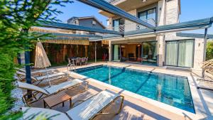 a swimming pool with chairs and a house at Söğüt 3 - 4 Bedroom with jacuzzi in Fethiye in Fethiye
