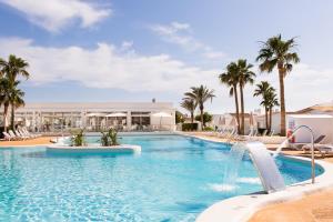 a swimming pool with palm trees and a resort at Sagitario Menorca Mar Adults only in Cala en Bosc